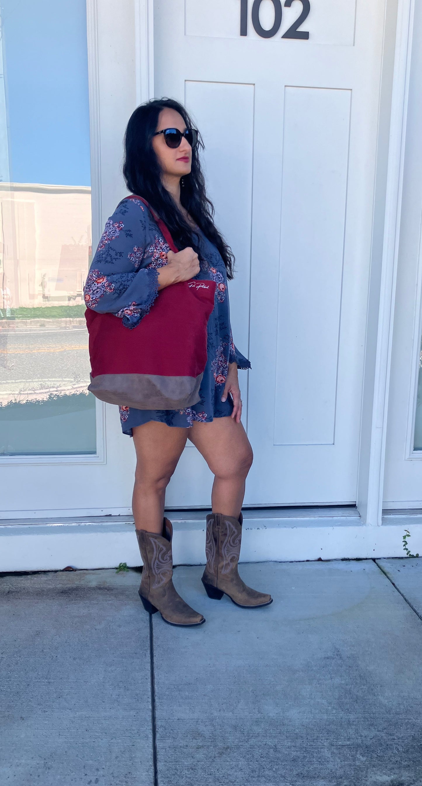Person standing in front of a white door with glass panels, wearing a floral dress and brown boots.