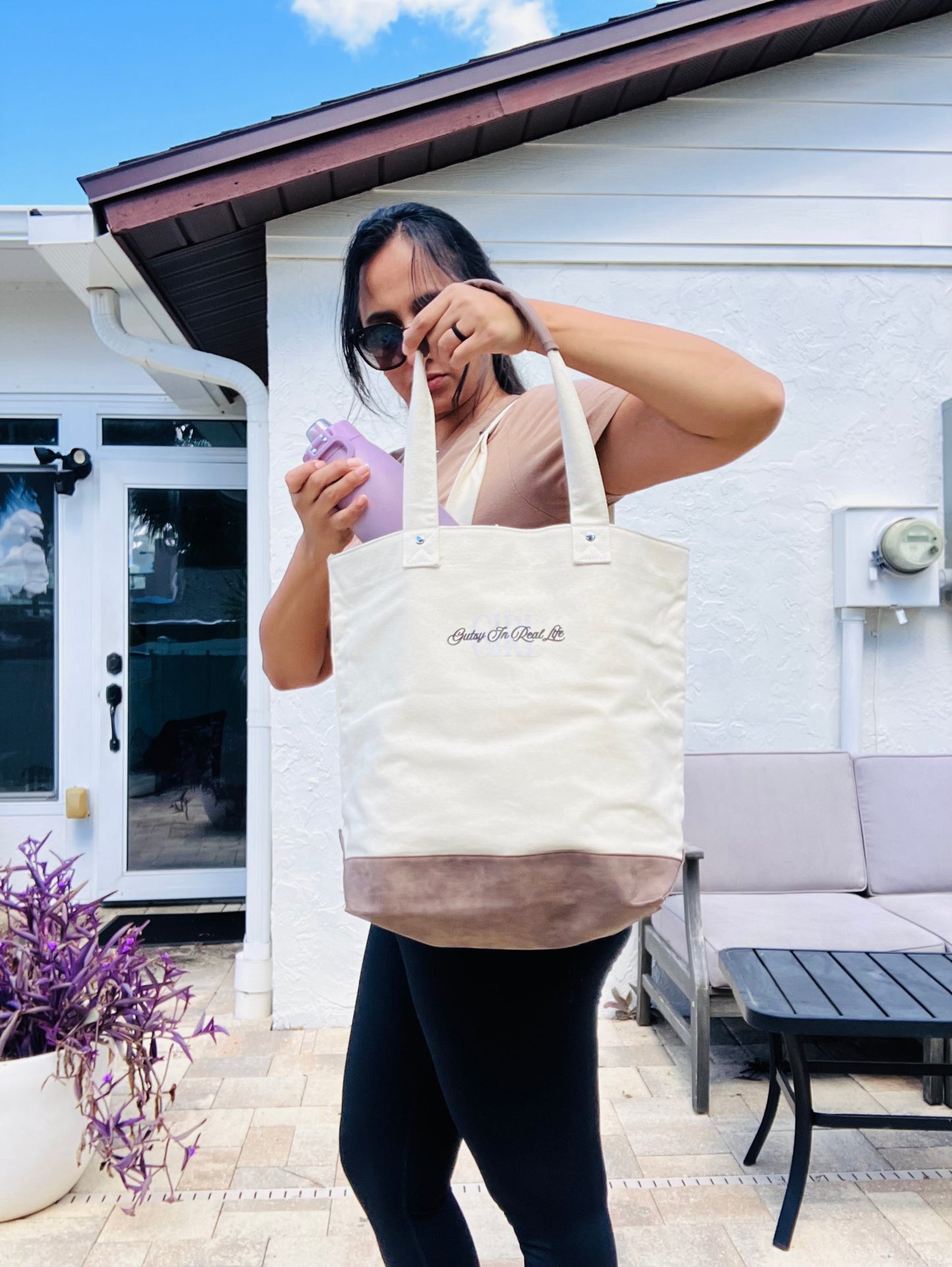 Person holding a tote bag with text outdoors