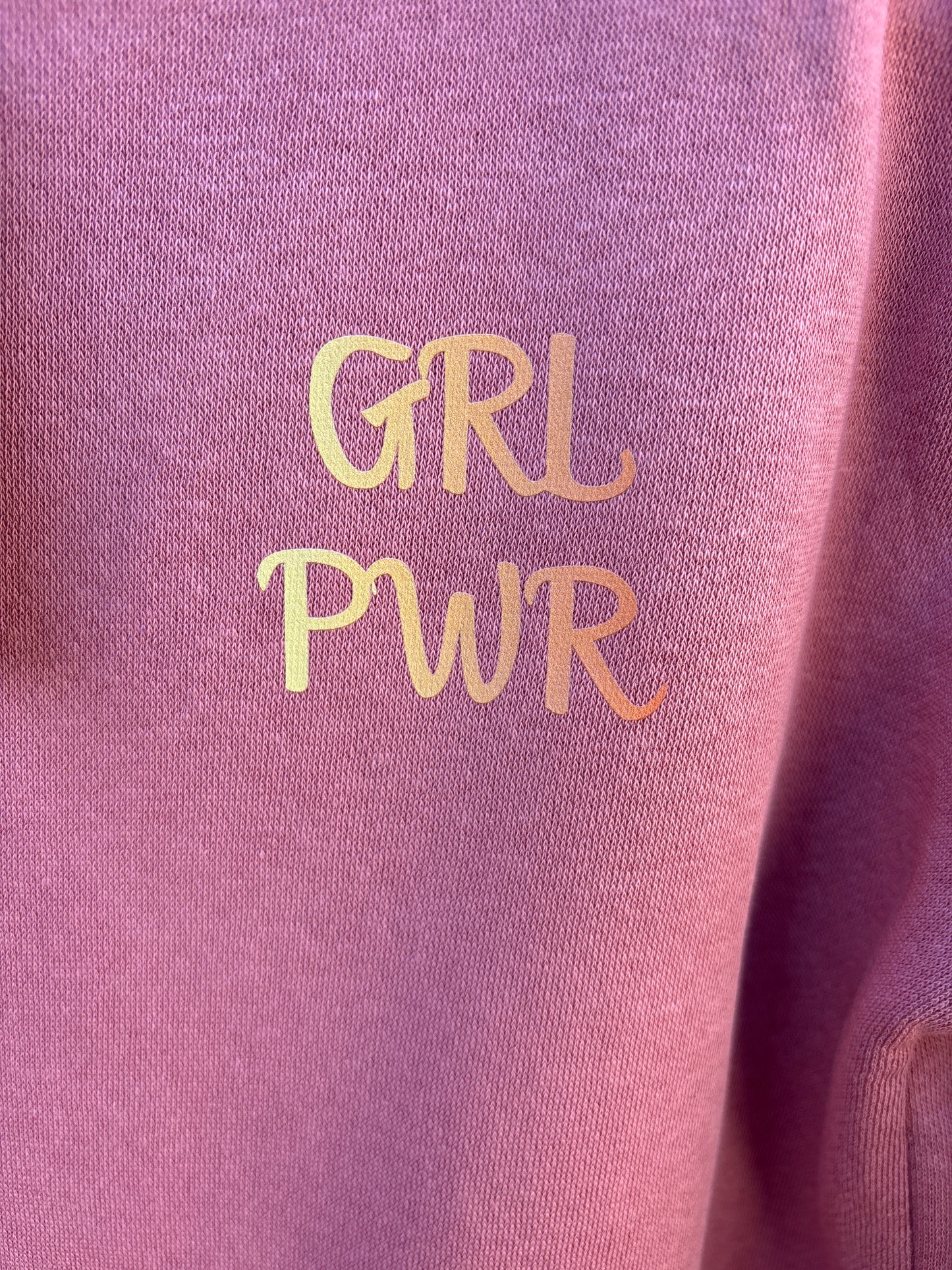 Pink fabric with 'GRL PWR' text in yellow on a close-up view