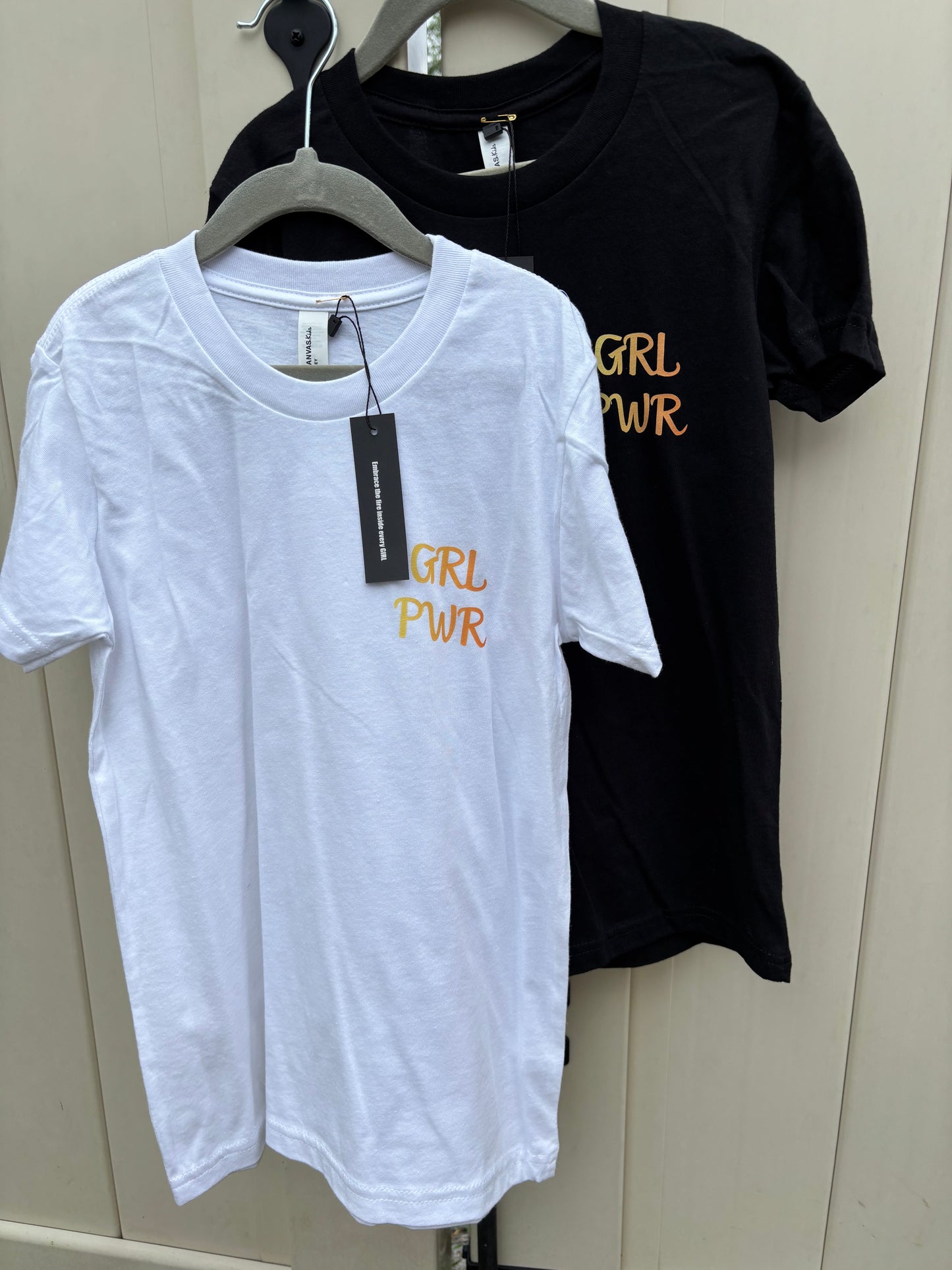 Black and white t-shirts with 'GRL PWR' text on a neutral background