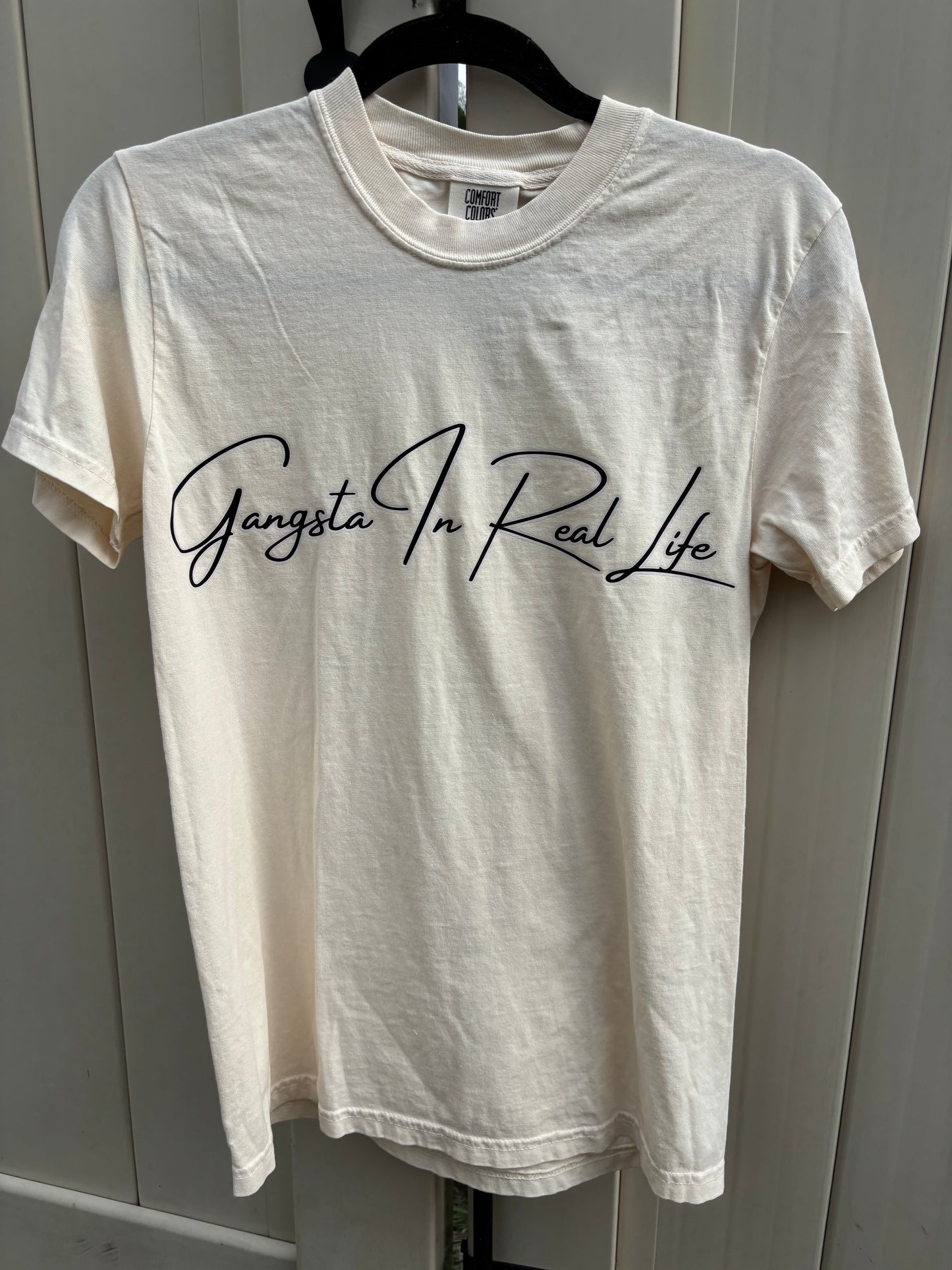 White t-shirt with black text on a hanger against a gray background