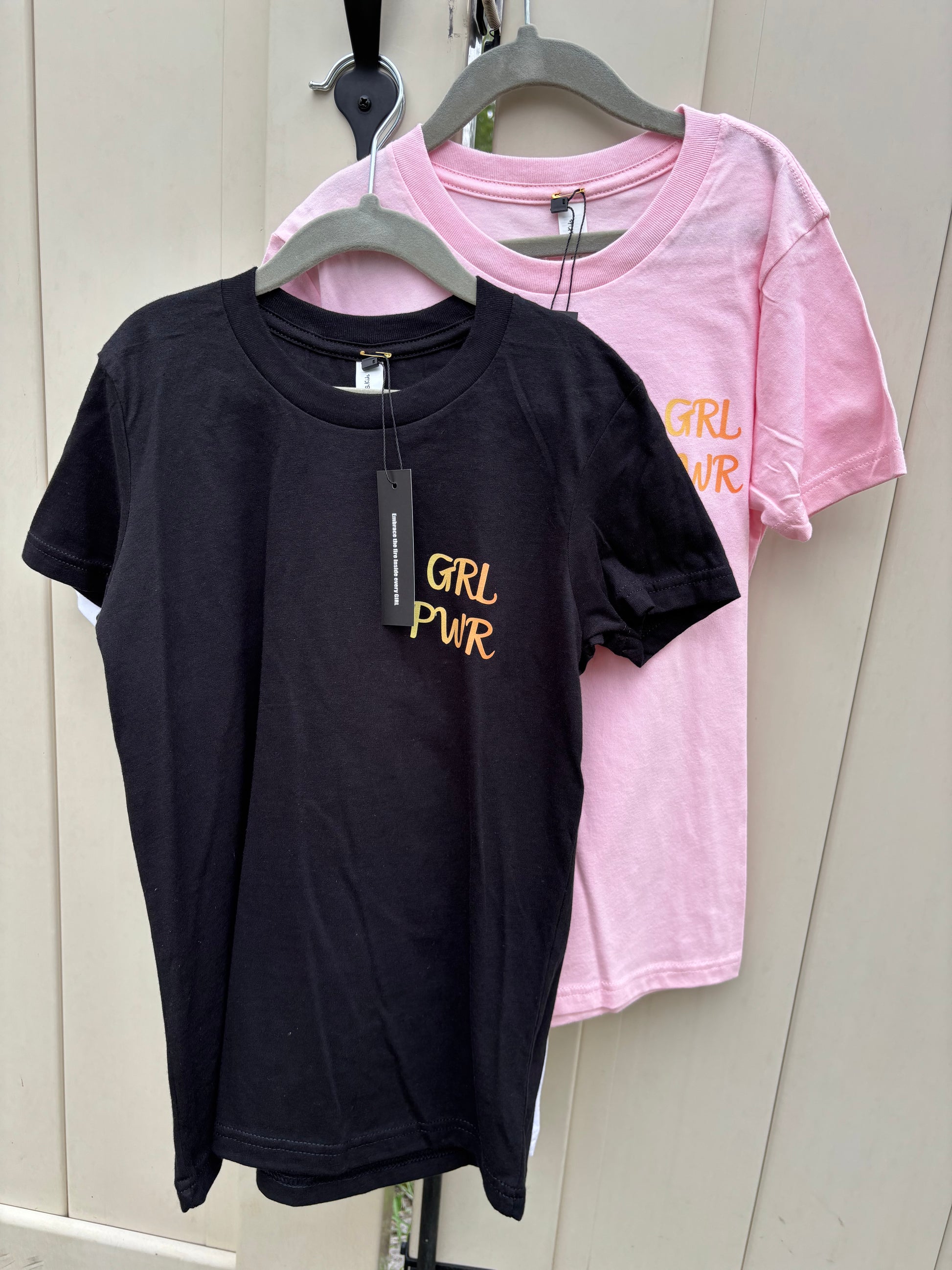Black t-shirt with 'GRL PWR' text on a wooden surface