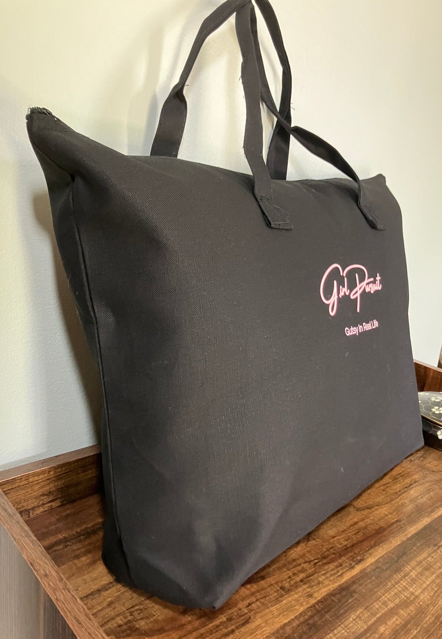 Black tote bag with a logo on a wooden surface